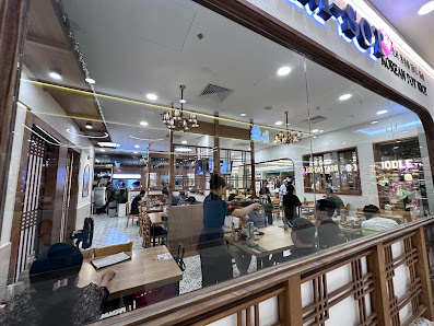 The image depicts the interior of a restaurant in Thao Dien, Saigon. It features a spacious dining area with wooden tables and chairs, some patrons se