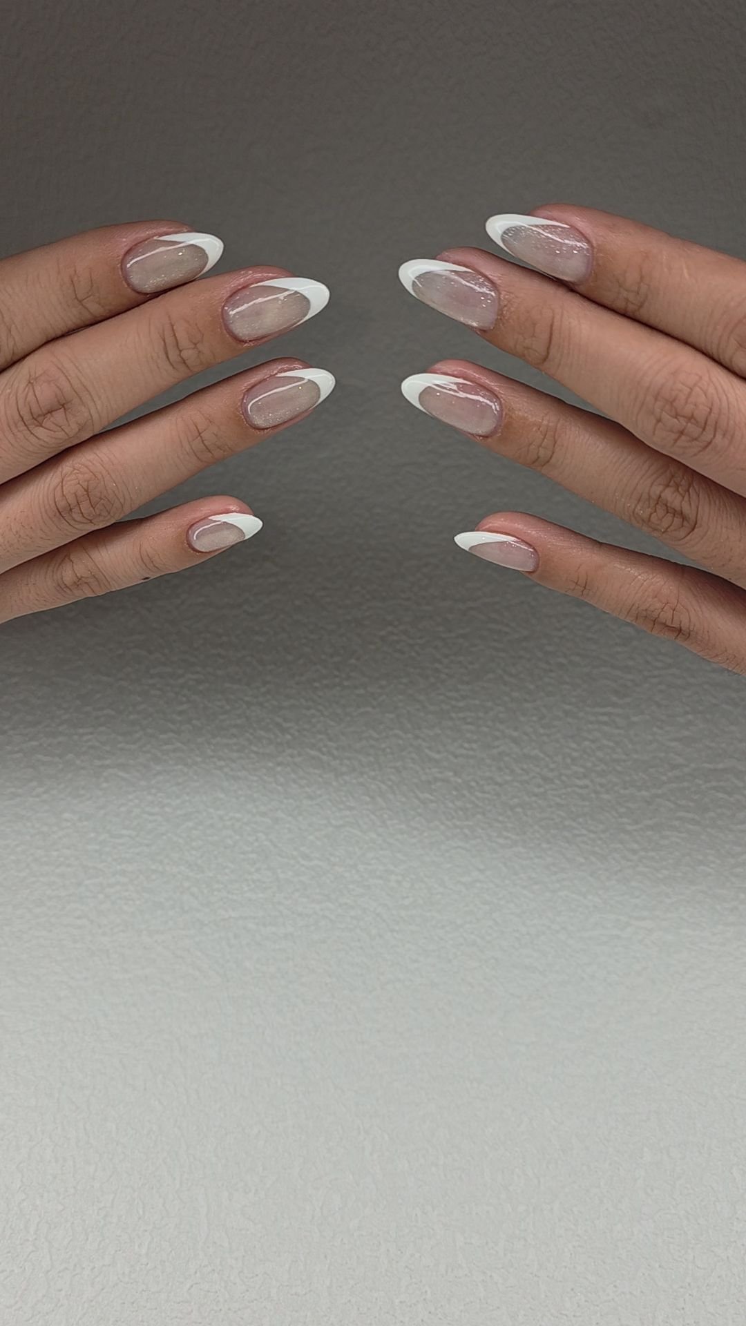 A close-up of a person's hands displaying manicured nails against a plain background.