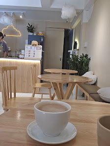 The image shows an interior view of a modern café or coffee shop in Thao Dien, Saigon. The setting includes wooden furniture and decor with plants add