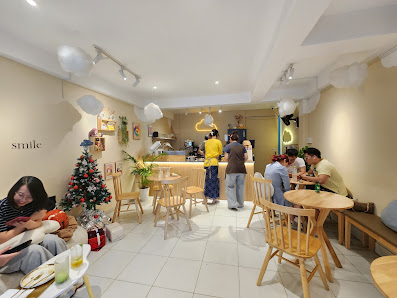 The image shows an interior view of a cozy café or restaurant named 'Smile'. The space is well-lit with warm lighting, and features wooden furniture i