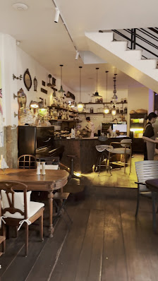 The image shows an interior view of a cozy café or restaurant in Thao Dien, Saigon. The space is warmly lit with wooden floors and tables, creating a 