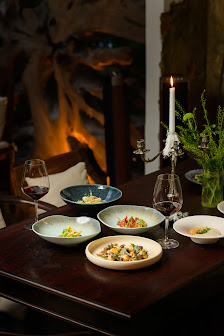 The image depicts a sophisticated dining setting on a wooden table adorned with various dishes and wine glasses in an indoor environment that suggests