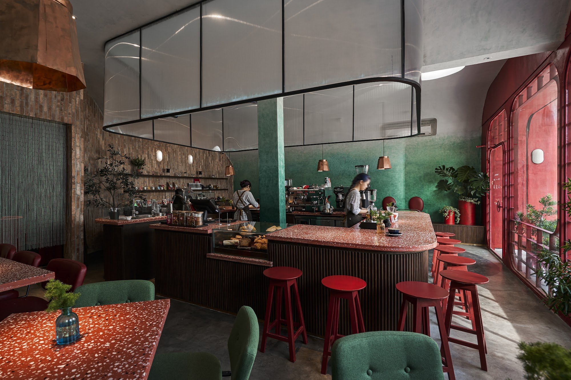 This image depicts an interior view of a modern café or restaurant. The space features industrial design elements such as exposed brick walls, copper 