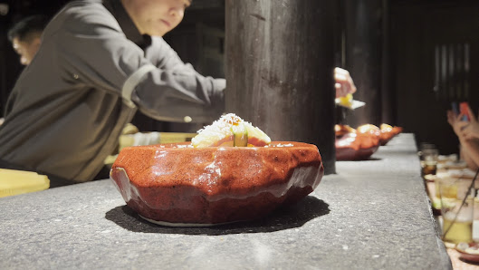 A close-up shot of a dessert in an elegant red ceramic bowl on a countertop with another similar dish blurred out in the background, suggesting this m