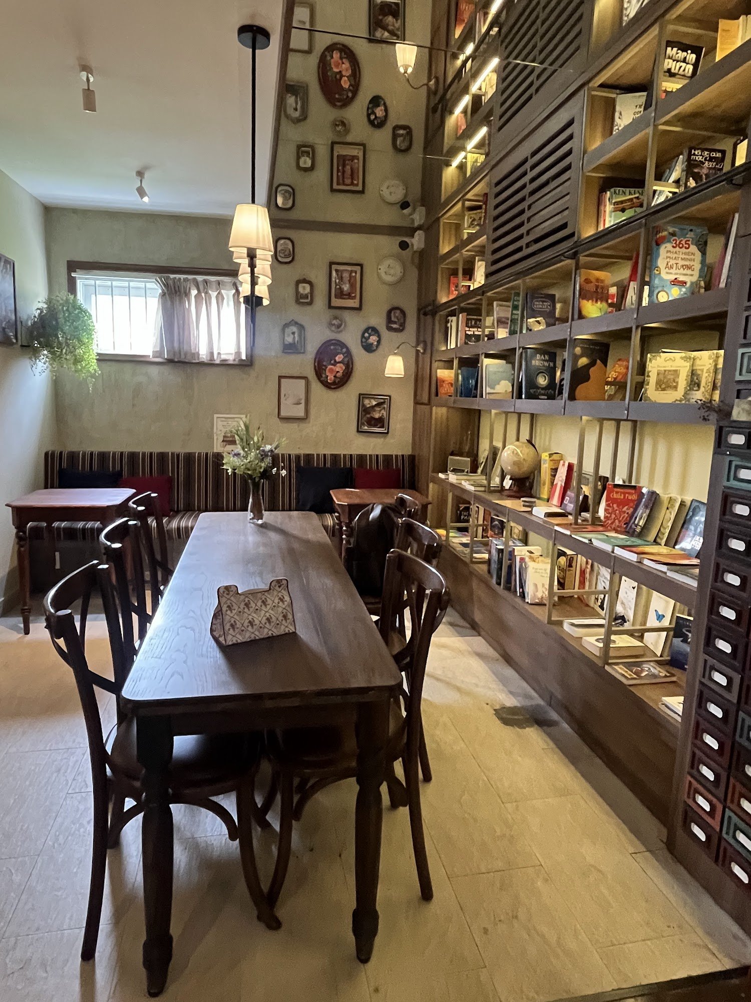 The image depicts an interior space that appears to be a cozy bookstore or café. The room is well-lit with natural light coming through the window, an