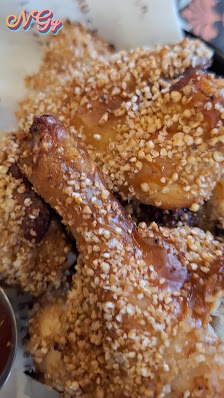 A close-up of a dish consisting of breaded and fried chicken wings coated in sesame seeds.