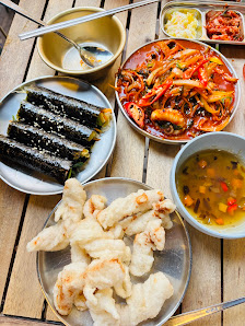 A variety of dishes served on a wooden table including what appears to be black fungus with sauce, prawns in red curry, shrimp and vegetable stir-fry,
