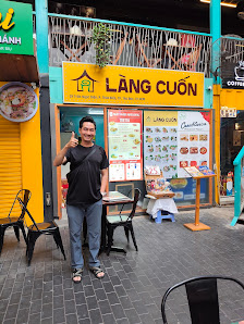 A man is standing outside a restaurant named 'LanG Cuon' giving a thumbs up sign while posing for the photo.