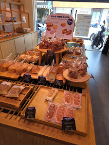 The image shows a display of various pastries and desserts on wooden trays in what appears to be the interior of a bakery or café.