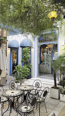 The image shows an outdoor seating area of a cafe or restaurant in Thao Dien, Saigon. The setting includes several round tables with metal frames and 
