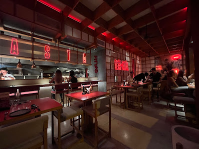The image depicts an interior view of a modern restaurant named 'ASTA.' The space is dimly lit with red neon lights and wooden accents, creating a coz