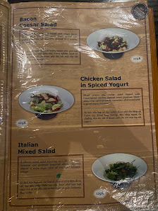 A menu board from a venue in Thao Dien, Saigon, featuring three salad dishes: Bacon Caesar Salad, Chicken Salad in Spiced Yogurt, and Italian Mixed Sa