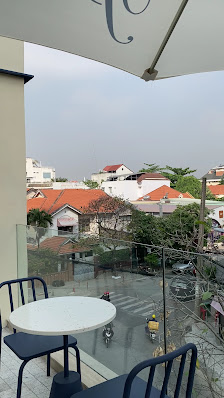 The image shows an outdoor seating area on a balcony overlooking residential buildings in Thao Dien, Saigon.