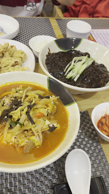 A table set for a meal featuring several dishes including what appears to be a bowl of soup with vegetables and meat in an orange broth, another dish 