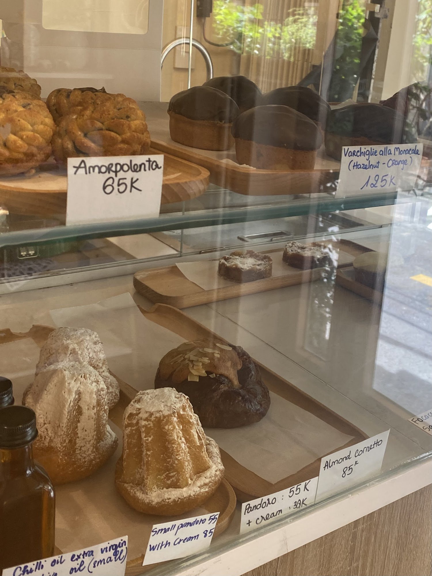 A display case in a bakery or café showing various baked goods and their prices.