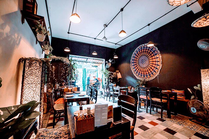 This image depicts an interior view of a restaurant or cafe in Thao Dien, Saigon. The space is decorated with eclectic and bohemian elements such as h