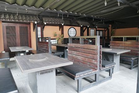 The image depicts an outdoor seating area of a venue in Thao Dien, Saigon. It features multiple tables with built-in grills or cooking surfaces, surro