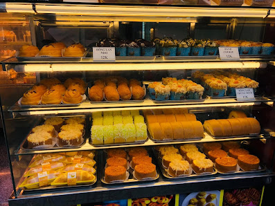 A display case in a bakery or dessert shop showcasing an assortment of pastries and cakes on multiple shelves.