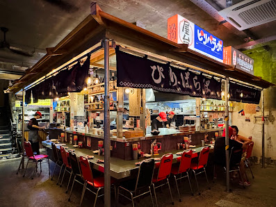 The image depicts the interior of a restaurant in Thao Dien, Saigon. It features a wooden canopy structure with black and red chairs arranged around a