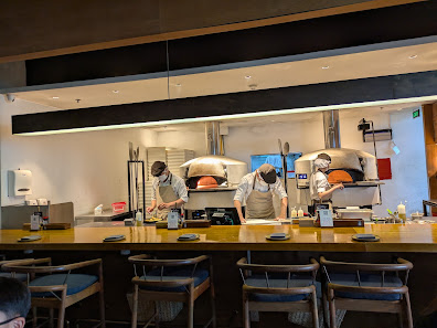 The image depicts the interior of a restaurant kitchen in Thao Dien, Saigon. Three chefs in white uniforms and aprons are working behind a long wooden