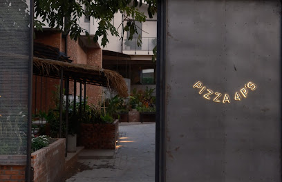 The image shows a neon sign that reads 'PIZZA4PS' on the exterior wall of what appears to be an urban eatery or restaurant in Thao Dien, Saigon.