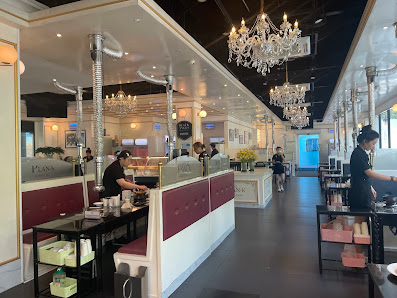 The image depicts the interior of a modern, upscale venue in Thao Dien, Saigon. It features a spacious layout with high ceilings, multiple crystal cha