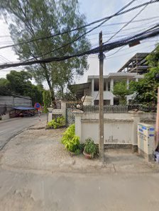 An outdoor street scene in Thao Dien, Saigon, featuring a curved road, a white residential house with a white fence, utility poles with overhead wires