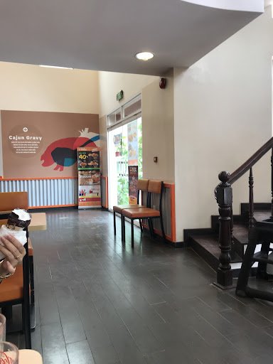 The image depicts the interior of a venue in Thao Dien, Saigon. It features a spacious room with dark tiled flooring, several wooden chairs with brown