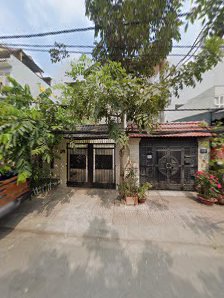 The image depicts the exterior of a residential or commercial property in Thao Dien, Saigon. It features a gated entrance with two large metal doors,