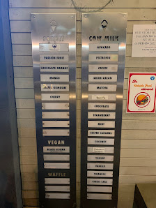 The image shows a section of an interior wall featuring two stainless steel menus for different types of milk and vegan products in what appears to be