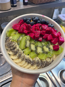 A bowl containing a fruit salad made up of sliced kiwi, blueberries, red berries (possibly strawberries or raspberries), and banana slices topped with