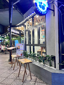 The image shows an exterior view of a restaurant named 'Pure Bowl' in Thao Dien, Saigon. The establishment has outdoor seating with wooden tables and 