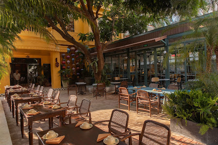 The image shows an outdoor seating area of a restaurant or cafe located in Thao Dien, Saigon. The setting is vibrant with yellow walls and greenery fr