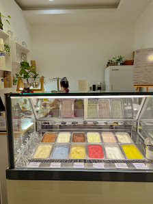 The image shows an interior view of a dessert shop or ice cream parlor displaying various flavors in their refrigerated display case.