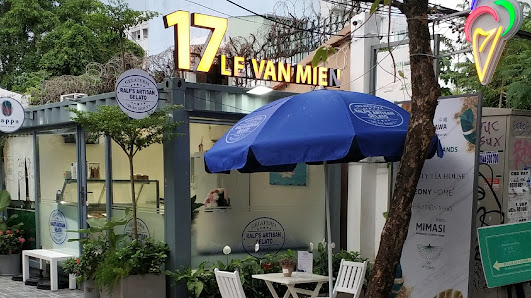 The image shows an exterior view of a cafe named '17 LEVAN-MIEN' with outdoor seating and a blue umbrella providing shade.