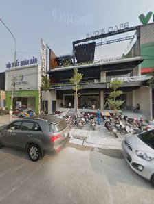 The image shows an exterior view of a commercial area in Thao Dien, Saigon with various shops and cafes including 'Budai Cafe'. There are parked cars