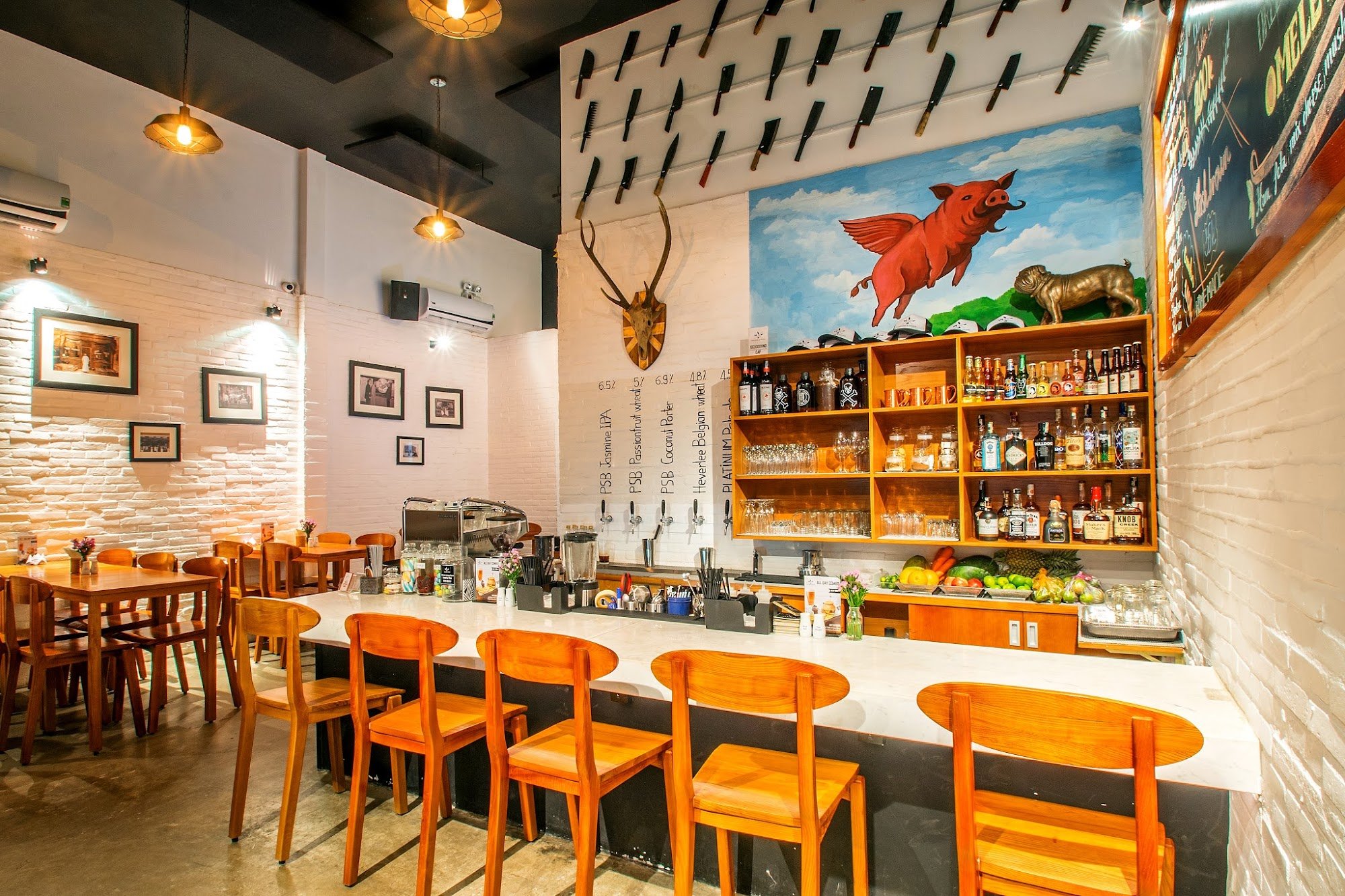 This image depicts an interior view of a bar and restaurant in Thao Dien, Saigon. The space features wooden chairs and tables with a modern industrial