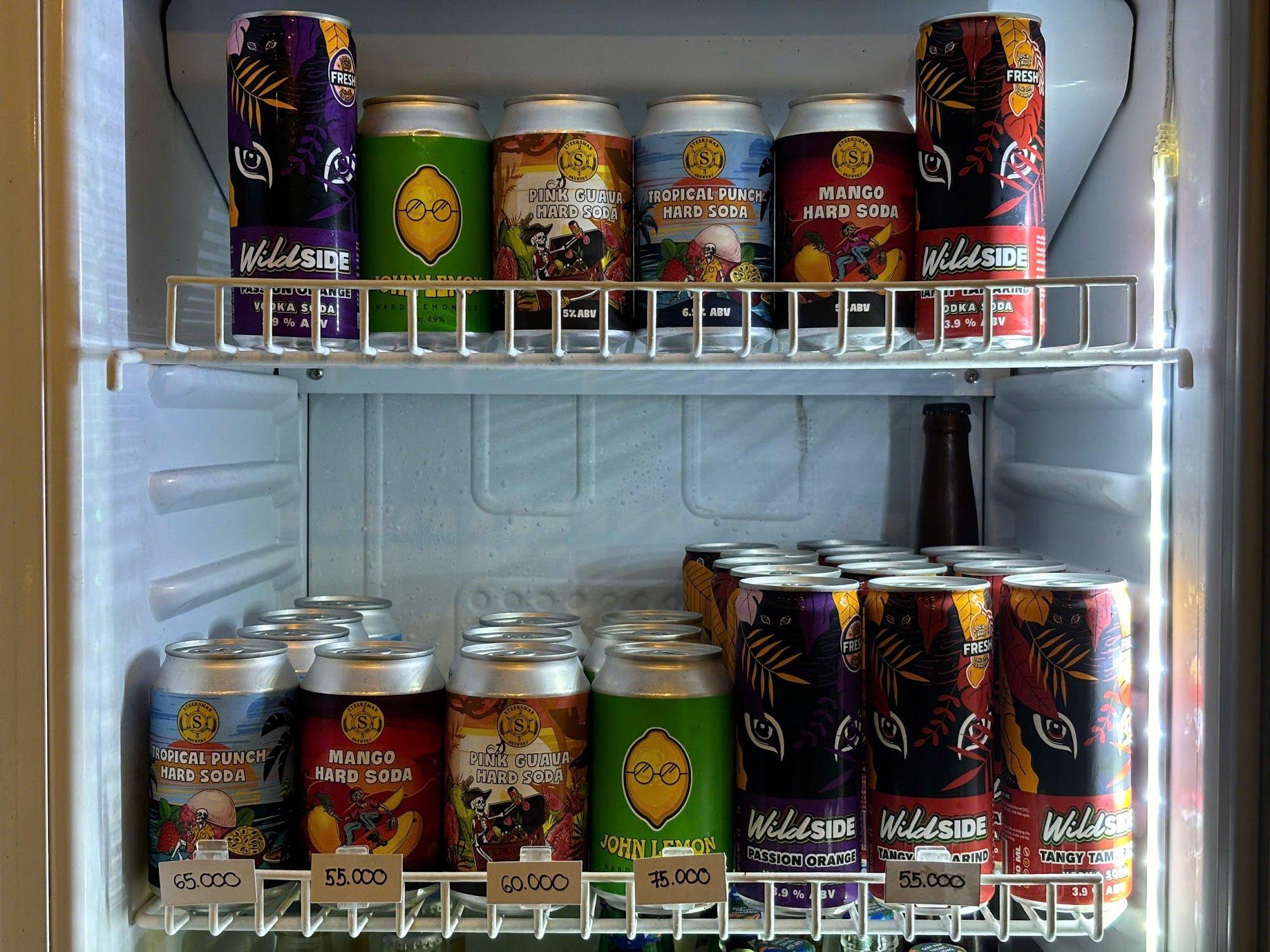 The image shows a variety of canned beverages displayed in an open refrigerator door at Thao Dien, Saigon.
