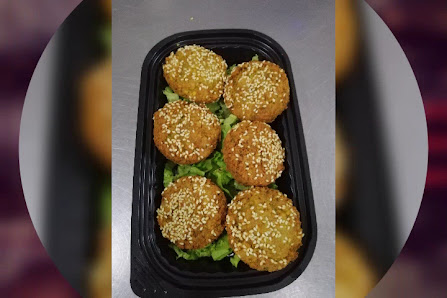 A black tray containing six golden-brown sesame seed-topped patties on a bed of green lettuce.