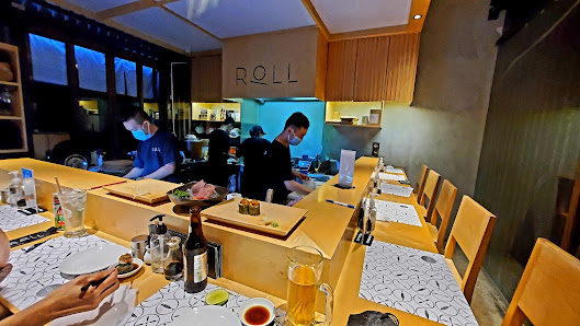 The image shows an interior view of a restaurant named 'ROLL'. The setting appears to be modern with wooden furniture and warm lighting, creating a co