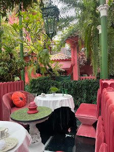 This image depicts an outdoor seating area of a restaurant or café in Thao Dien, Saigon. The setting is vibrant and colorful with red furniture includ