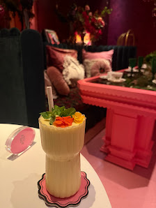 The image shows a cozy interior setting featuring vibrant pink and red tones on the furniture against a darker backdrop with decorative elements like 