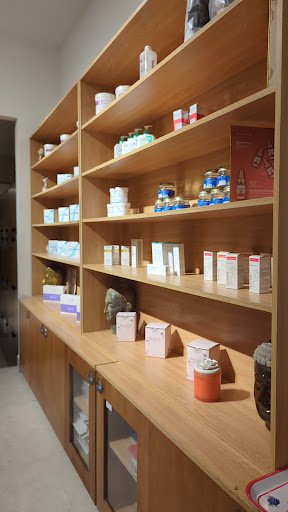 The image shows a well-organized wooden shelving unit filled with various health supplements and products in Thao Dien, Saigon.