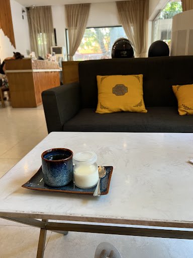 The image shows a modern interior setting of what appears to be a lounge or waiting area in Thao Dien, Saigon. A dark-colored sofa with yellow cushion