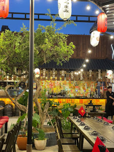 The image shows an interior view of a restaurant at night time. The decor includes wooden elements and red lanterns hanging from the ceiling, with var