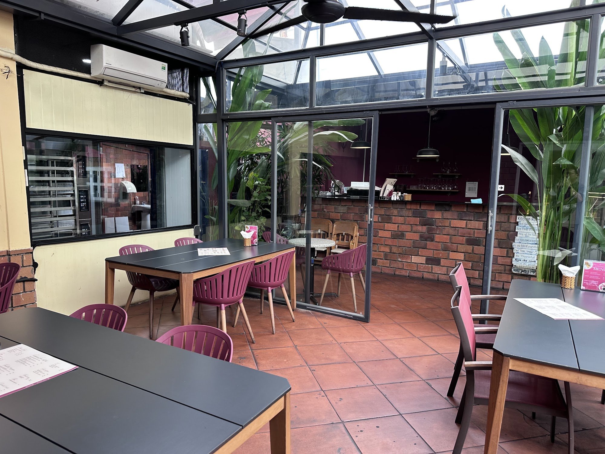 The image shows an indoor seating area of a restaurant or café in Thao Dien, Saigon. The space is furnished with dark tables and chairs accented by pi