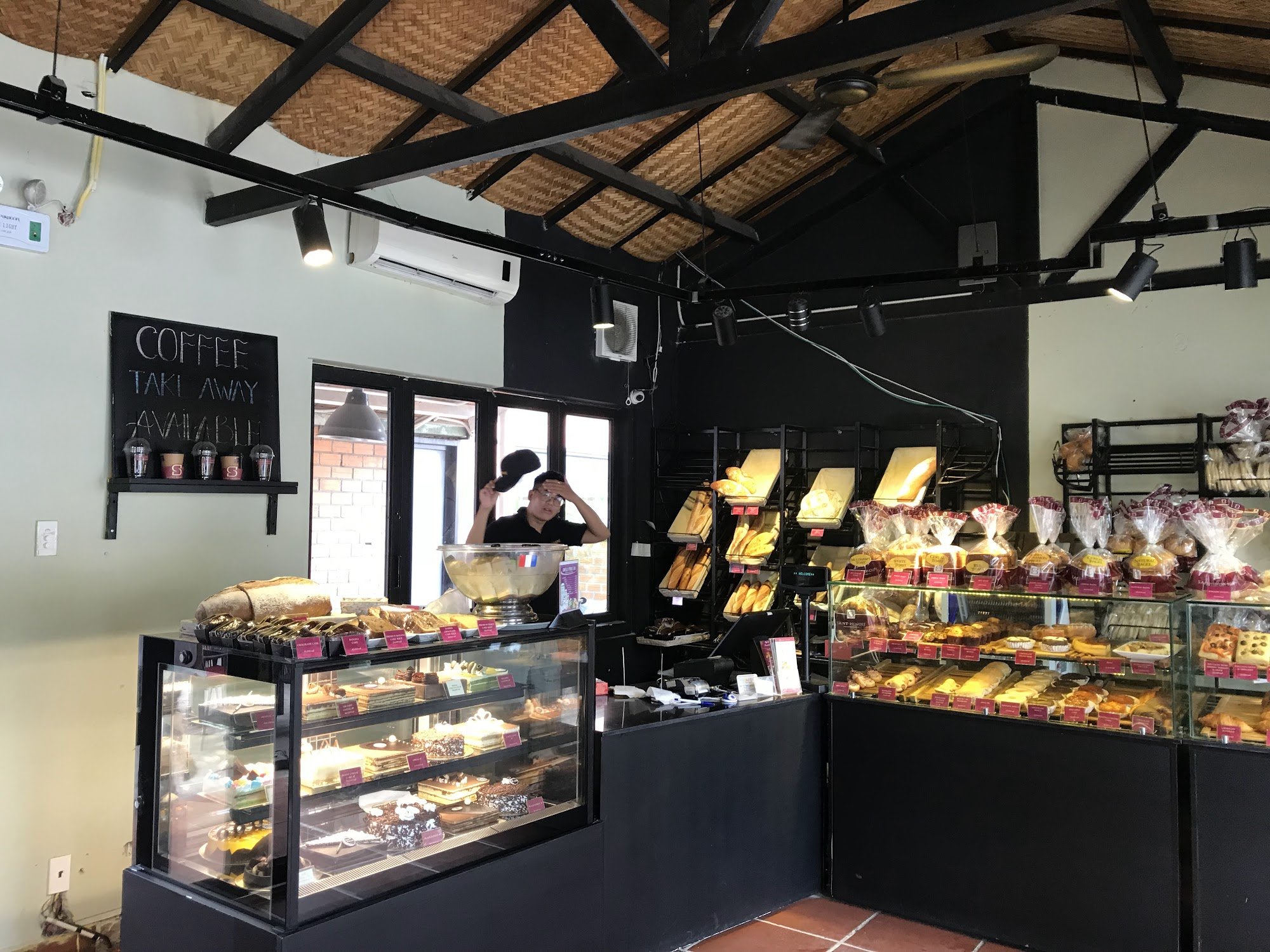 The image shows an interior view of a bakery or café named 'Coffee Take Away Available'. The establishment has a rustic aesthetic with exposed wooden 
