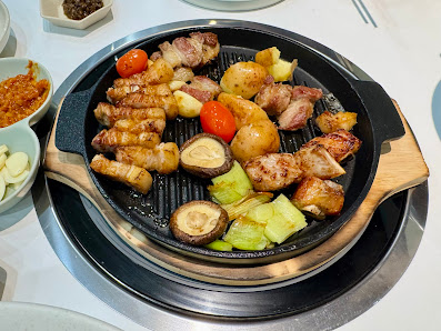 A grill pan filled with various grilled vegetables and meats on a tabletop stove.