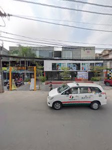 A white car parked on a street in front of commercial buildings under an overcast sky.