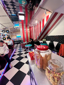 The image shows an interior of a diner-style venue characterized by retro decor including red and white striped walls, black-and-white checkered floor